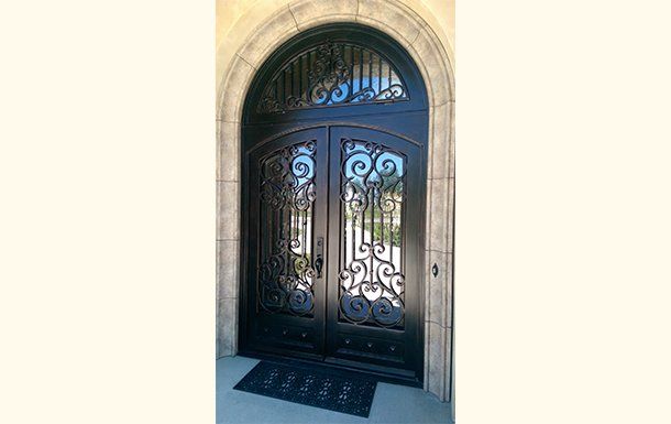 A black wrought iron door with a black mat underneath it.