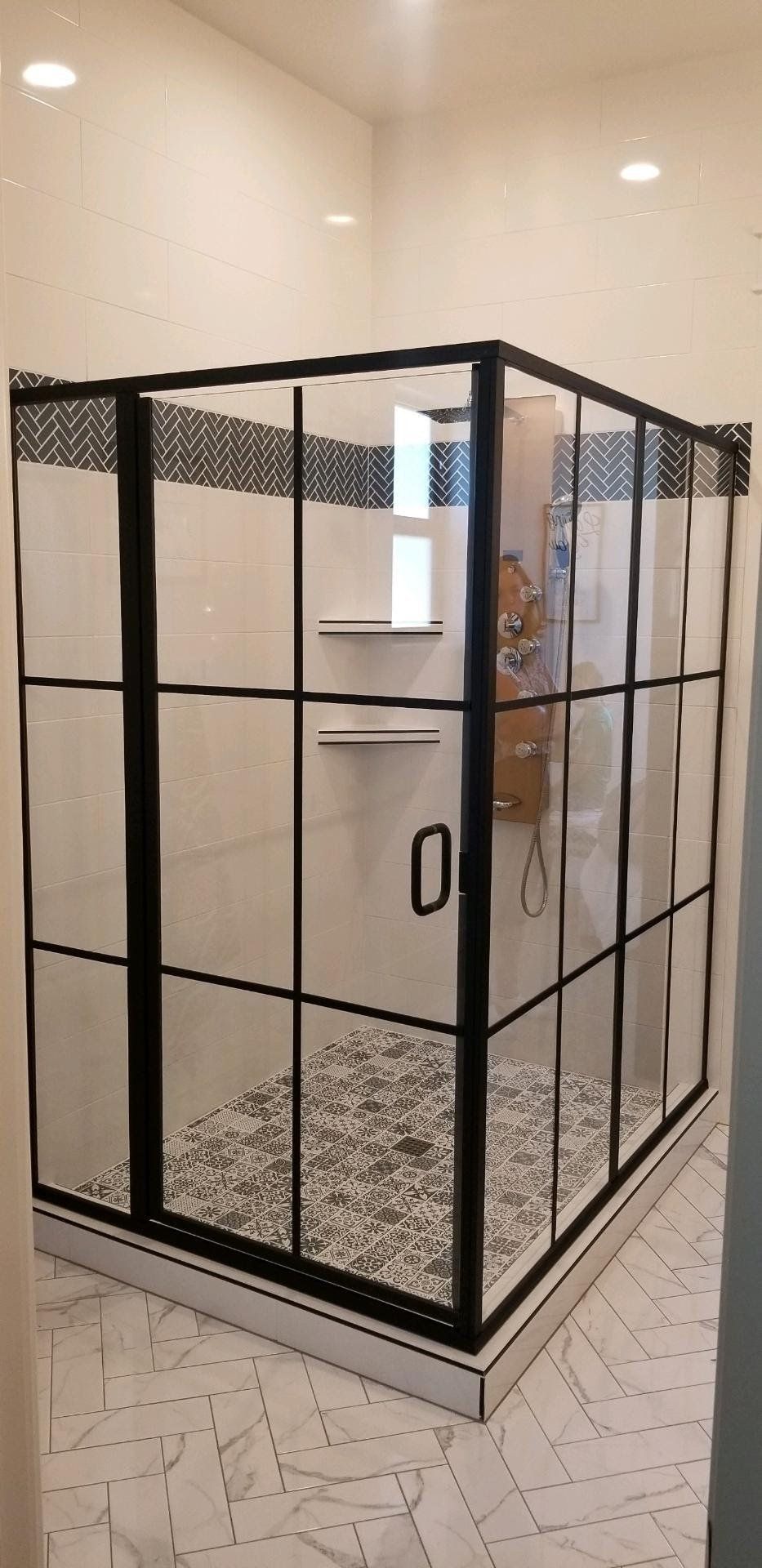 A shower stall with a black frame and clear glass doors in a bathroom.