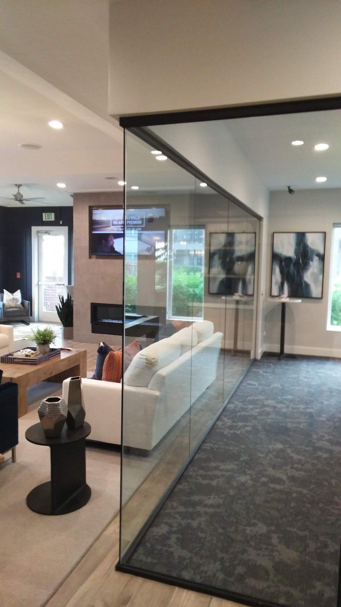A living room with a glass wall between the living room and dining room.