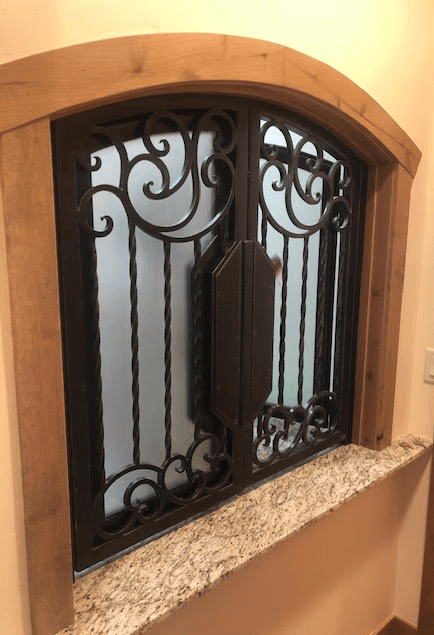 A wrought iron window with a wooden frame and a granite counter top.