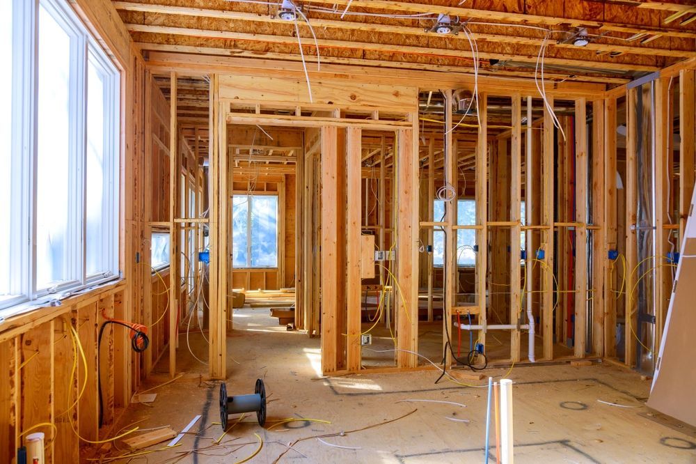 Unfinished home interior with exposed wooden framing, insulation, and a large window letting in daylight