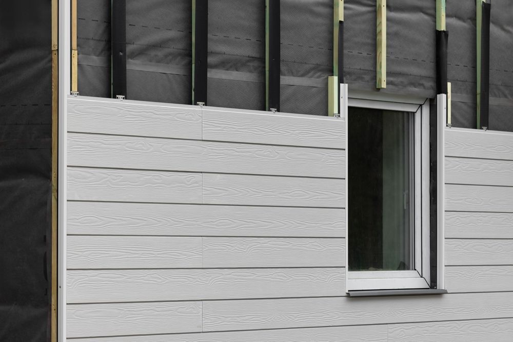 Exterior wall under construction with gray siding and a single window opening