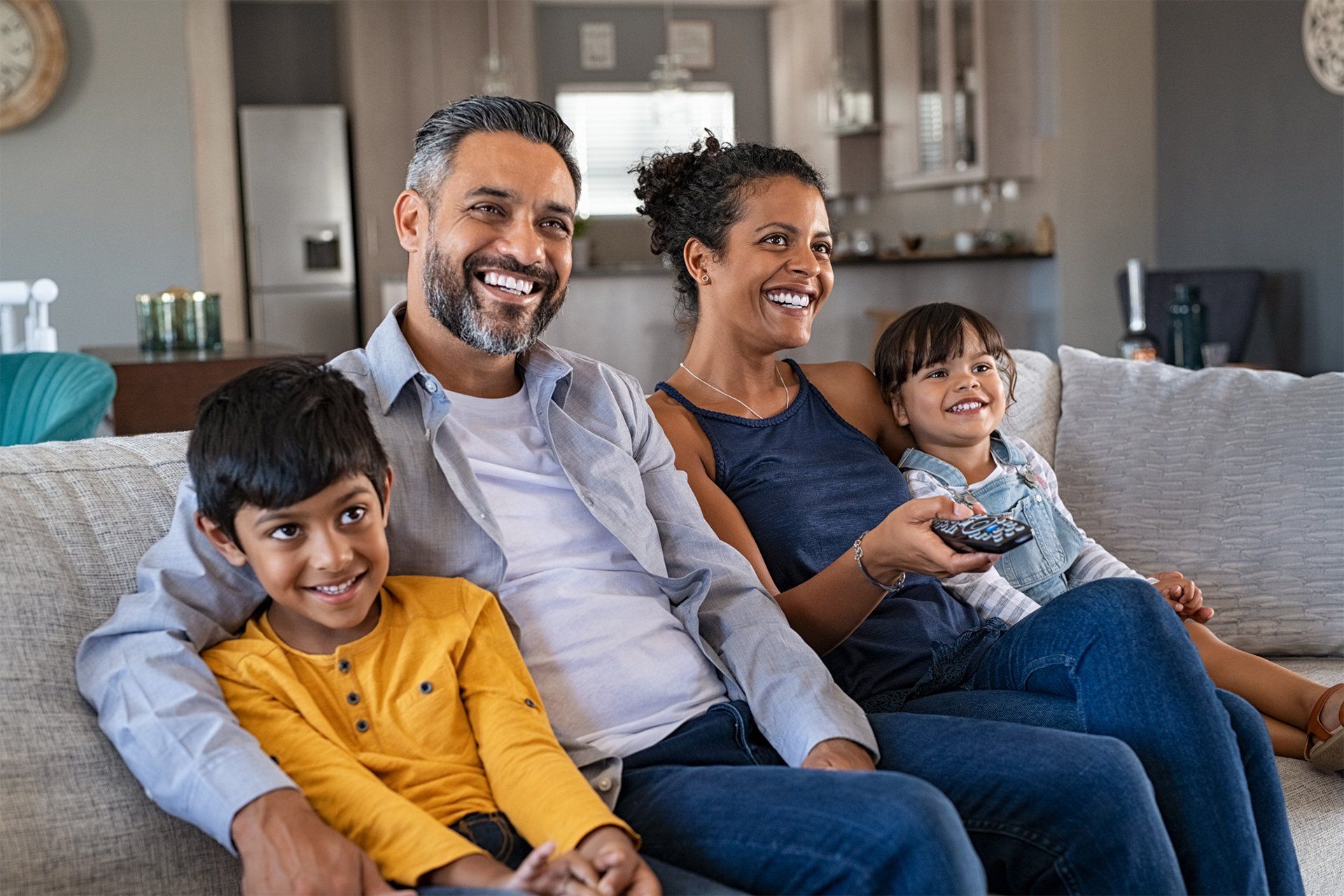 A happy Family sitting on a sofa and Watching Movie At Home