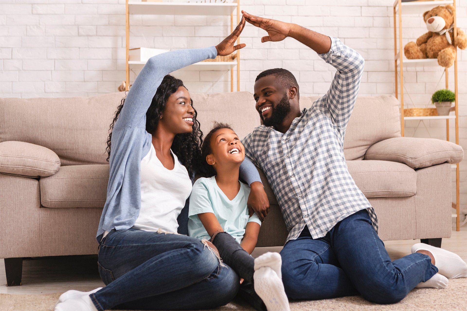 A couple with their daughter sitting on the floor at home, depicting a family moment in a domestic setting