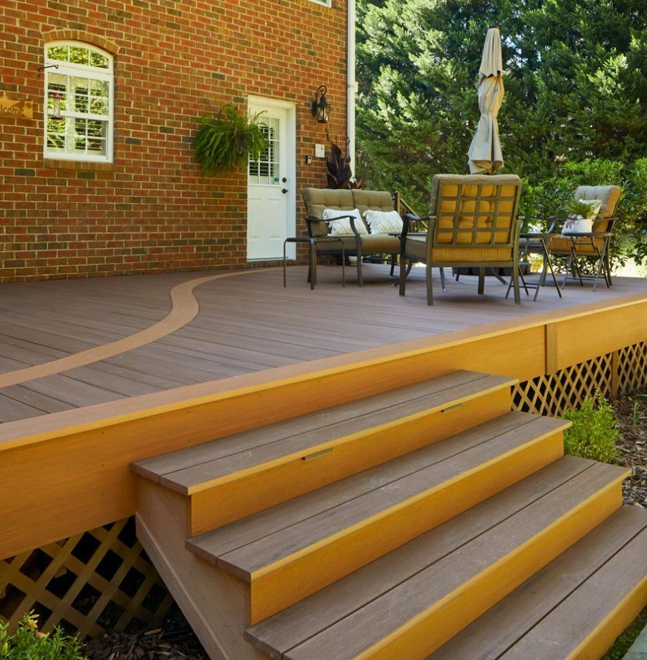 Composite deck with steps, tan and brown. Outdoor seating area near a brick house.