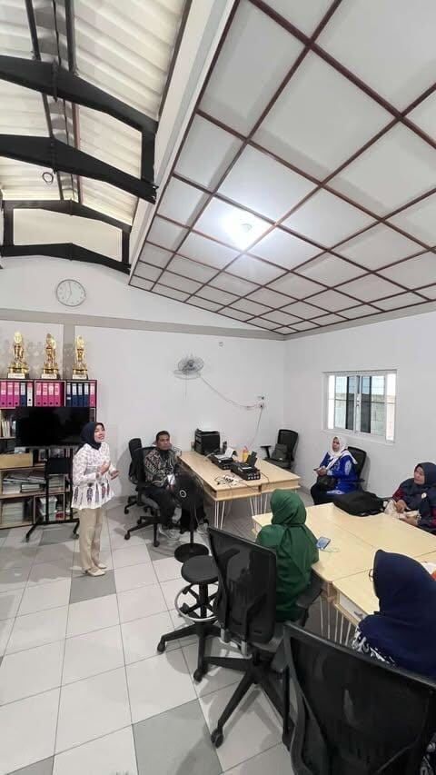 A presentation taking place in a room with women wearing headscarves; a presenter speaks at the front.