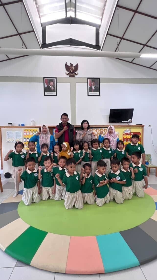 Children in blue skirts and white shirts pose with adults outdoors.