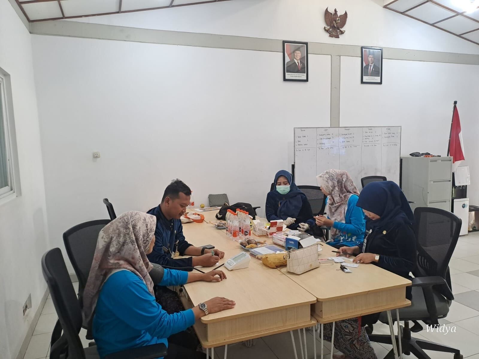 People in a meeting at a table, watching a presentation on a screen.