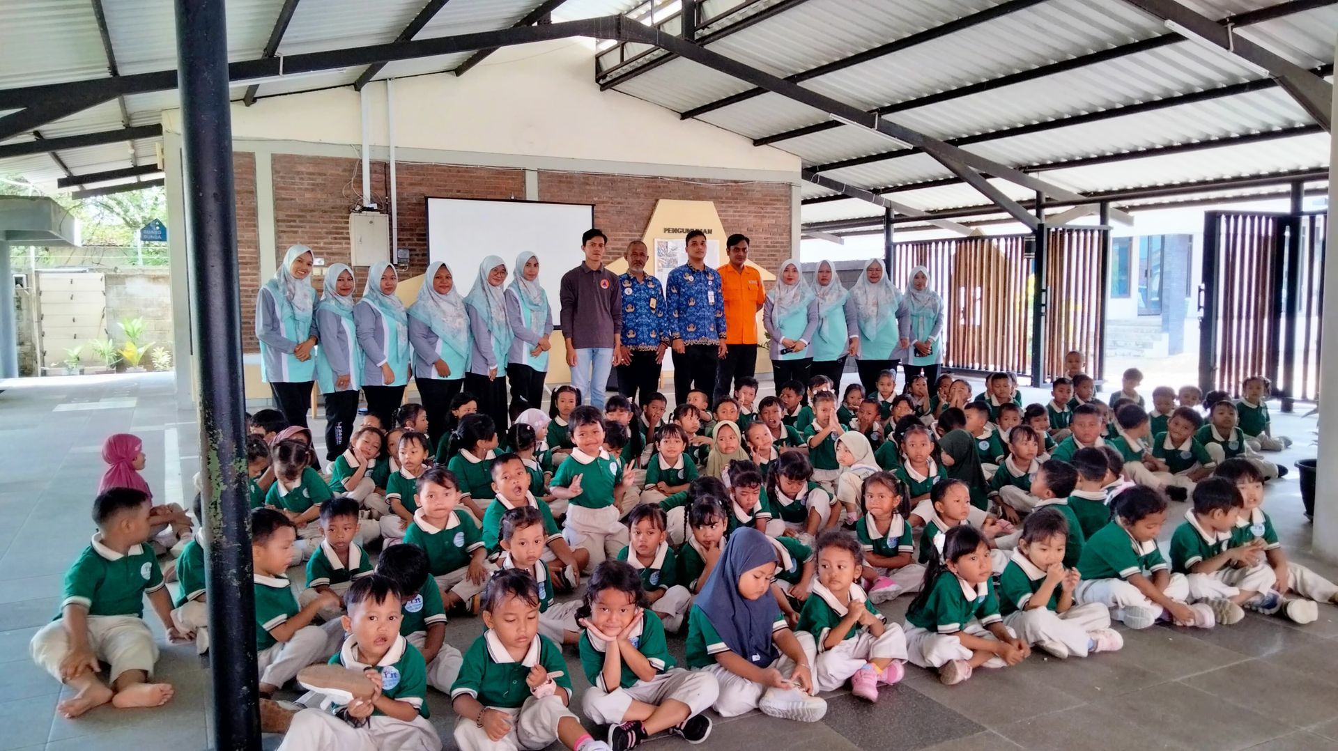 A large group of children are sitting on the floor in a room.