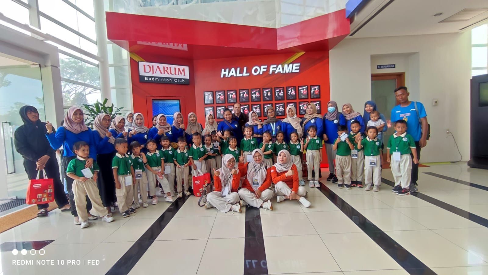 A group of children are posing for a picture in front of a hall of fame.