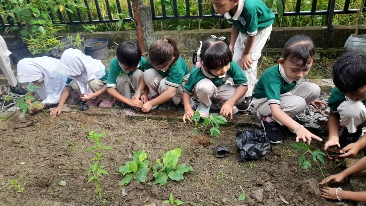 Children in green shirts and tan pants line up on red carpet. Indoor event.