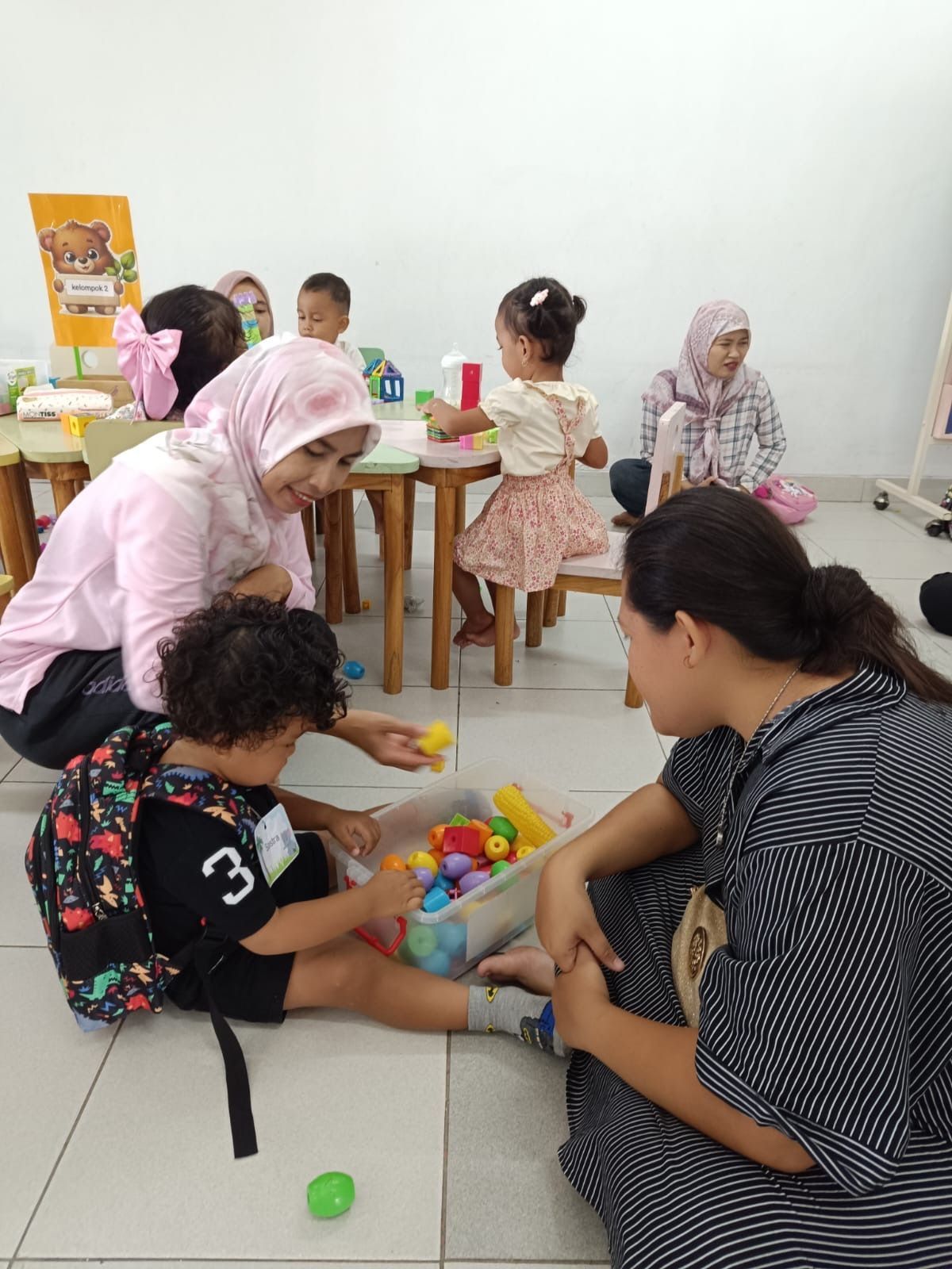 Children in green shirts and tan pants line up on red carpet. Indoor event.