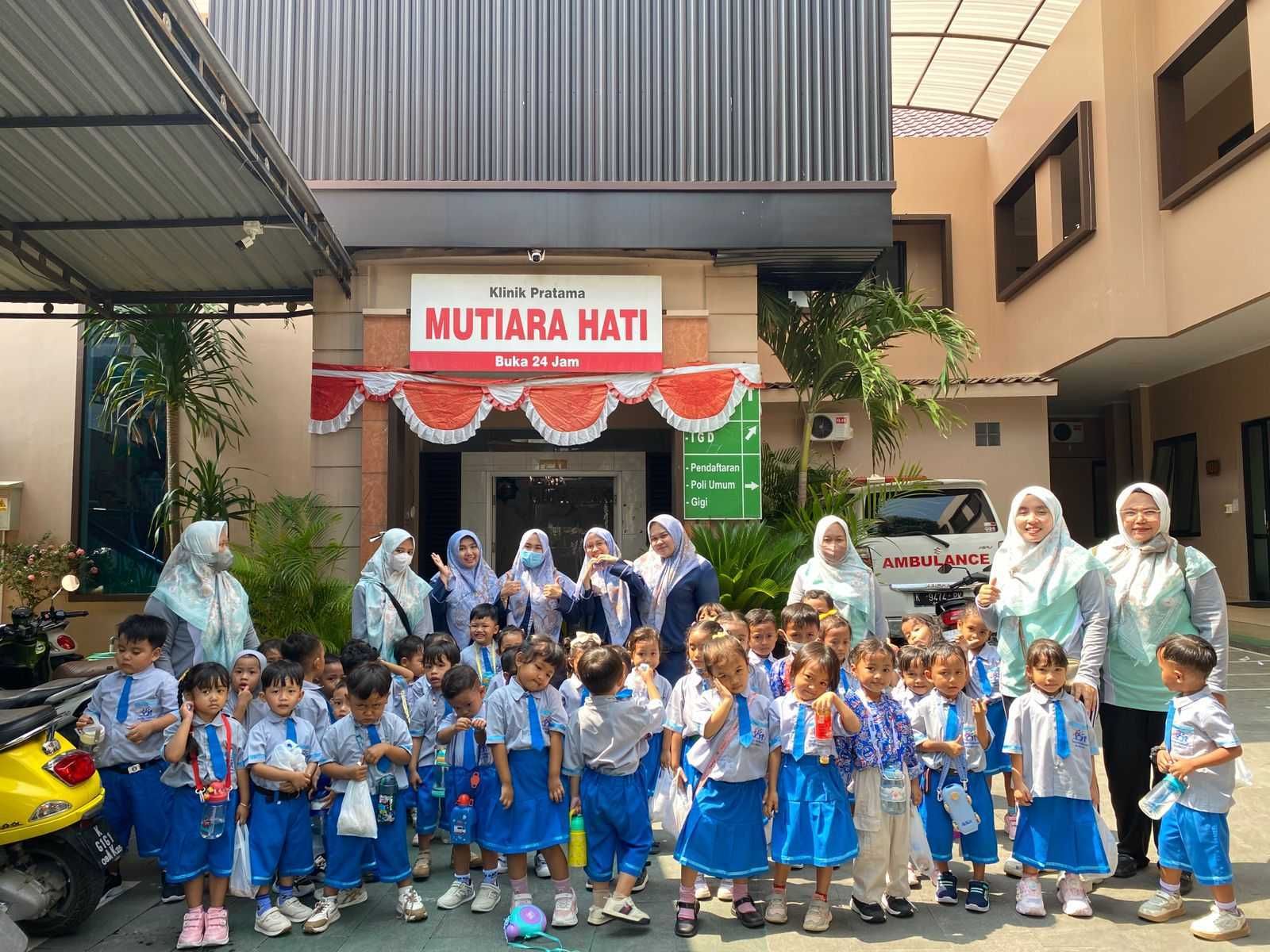 Group of children in blue uniforms with teachers outside