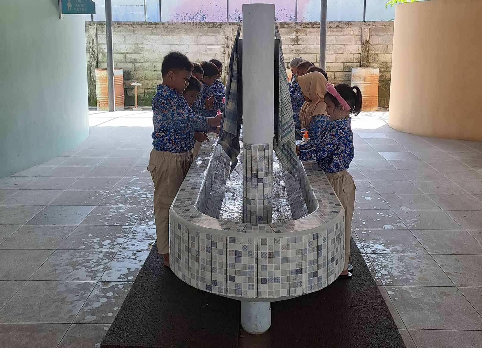 A group of children are washing their hands in a sink.