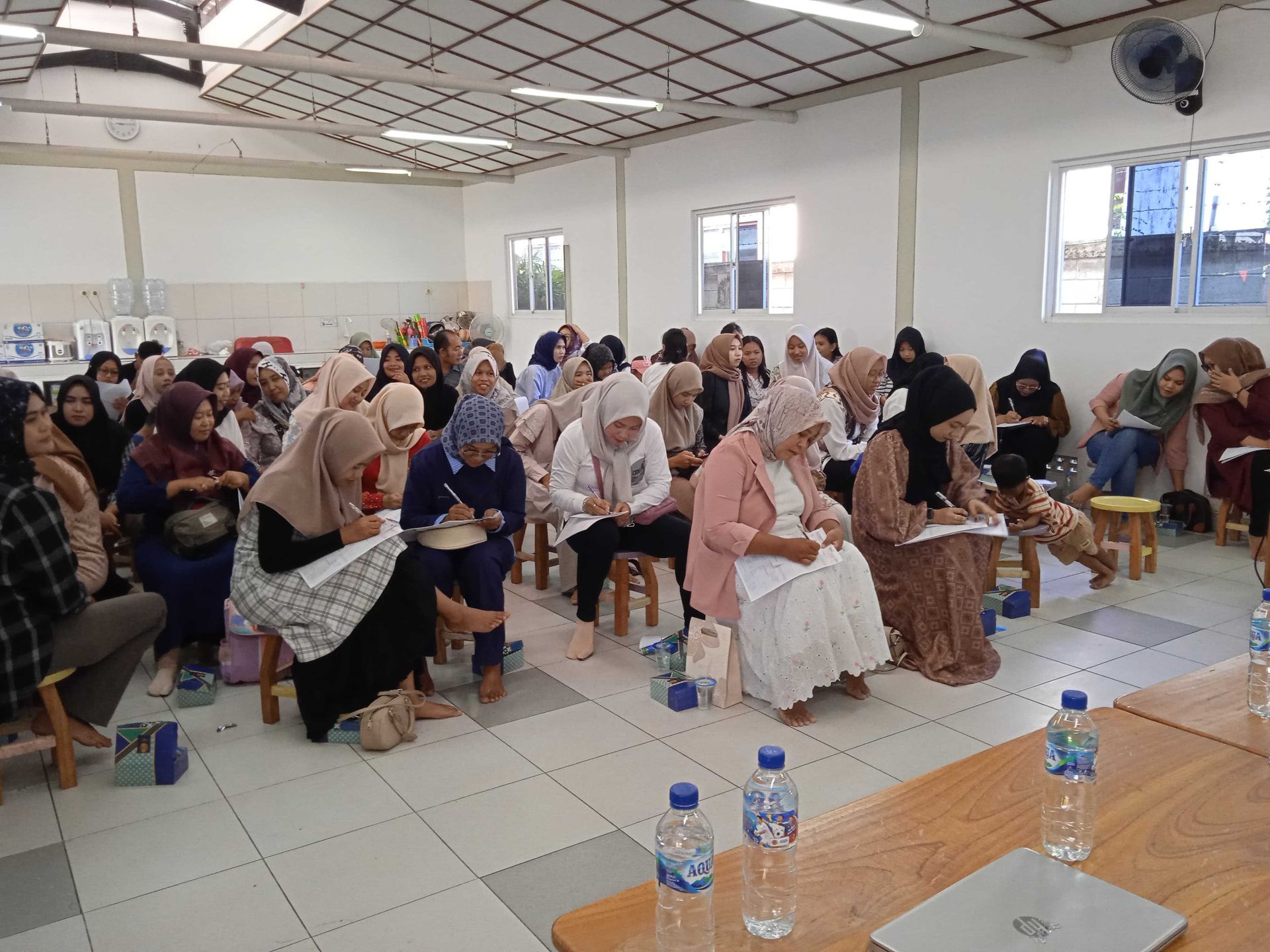 A group of women in hijabs take notes in a brightly lit room.