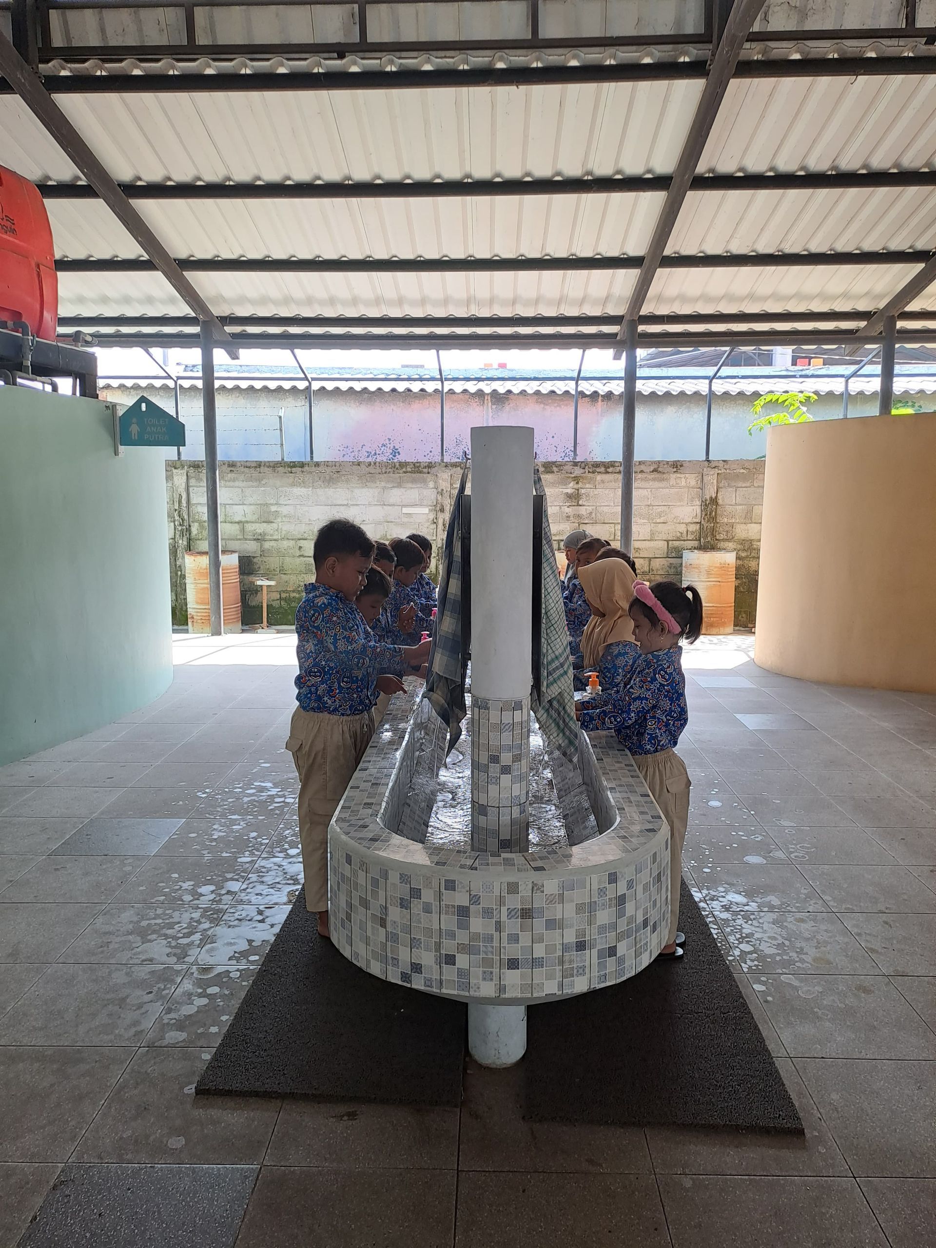 A group of children are washing their hands in a sink.