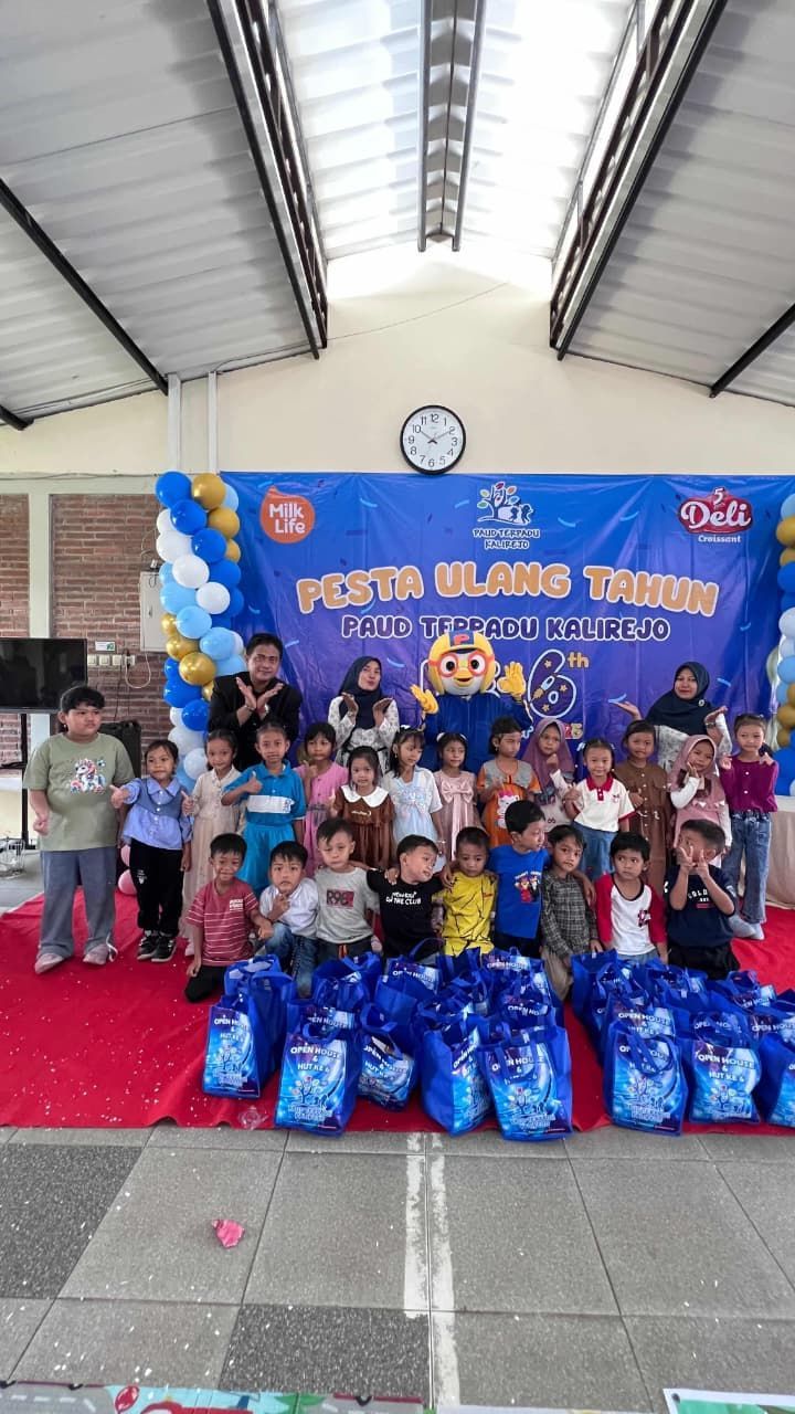 Children at a party with gifts and a banner. Blue and gold decorations, outdoor setting.