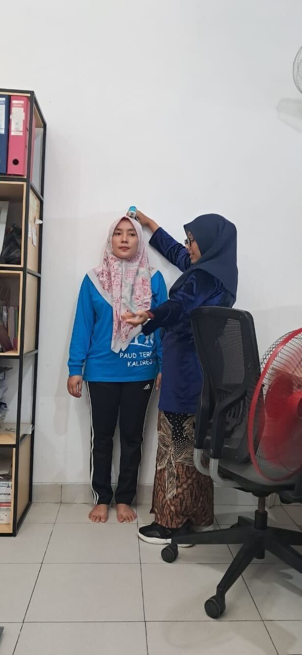 A presentation taking place in a room with women wearing headscarves; a presenter speaks at the front.