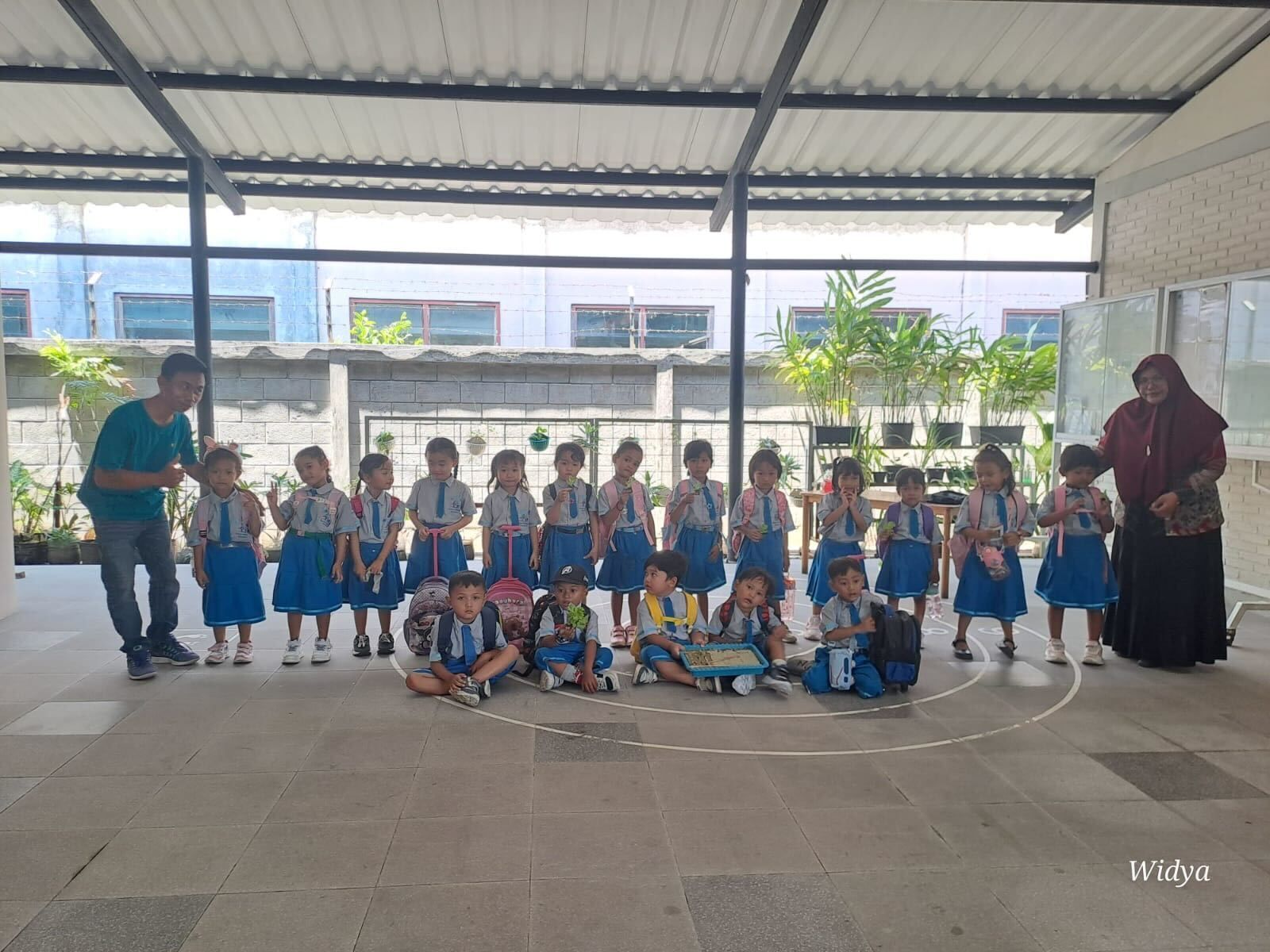 Children sitting in a circle listening to a teacher holding a stuffed animal.