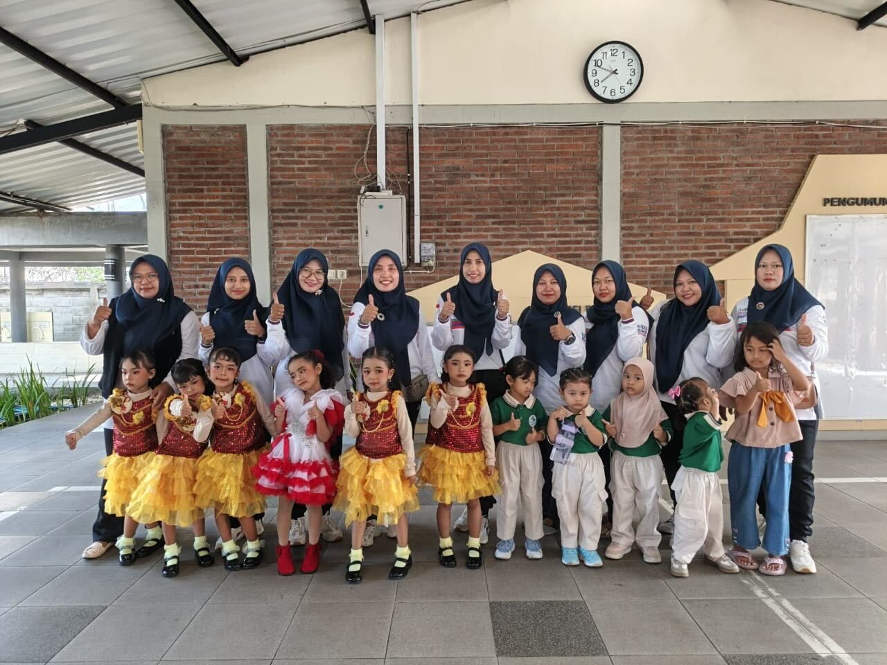 Children in costumes with teachers, posing outdoors.