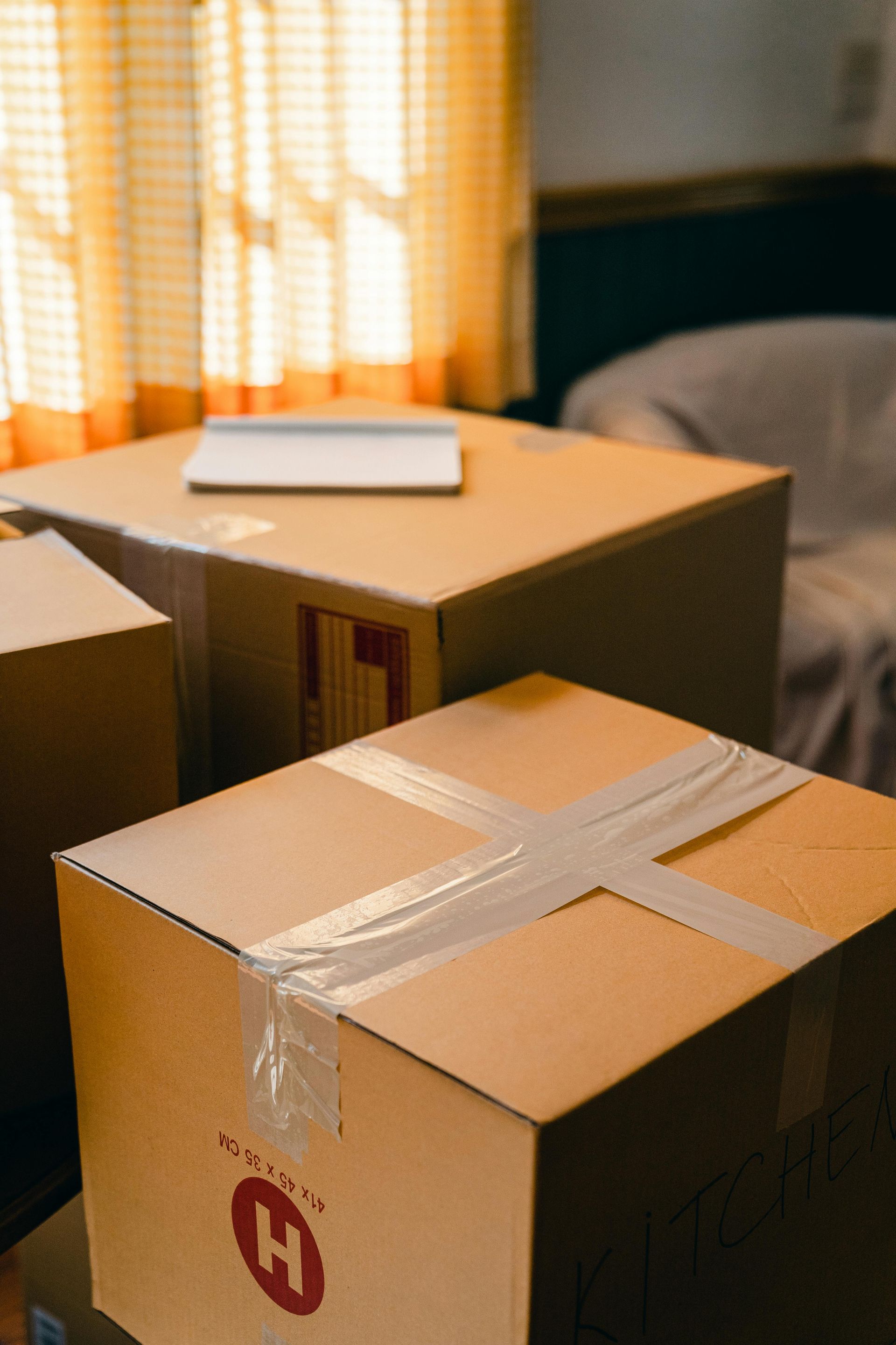 Cardboard boxes taped, ready for moving, with a laptop on top.
