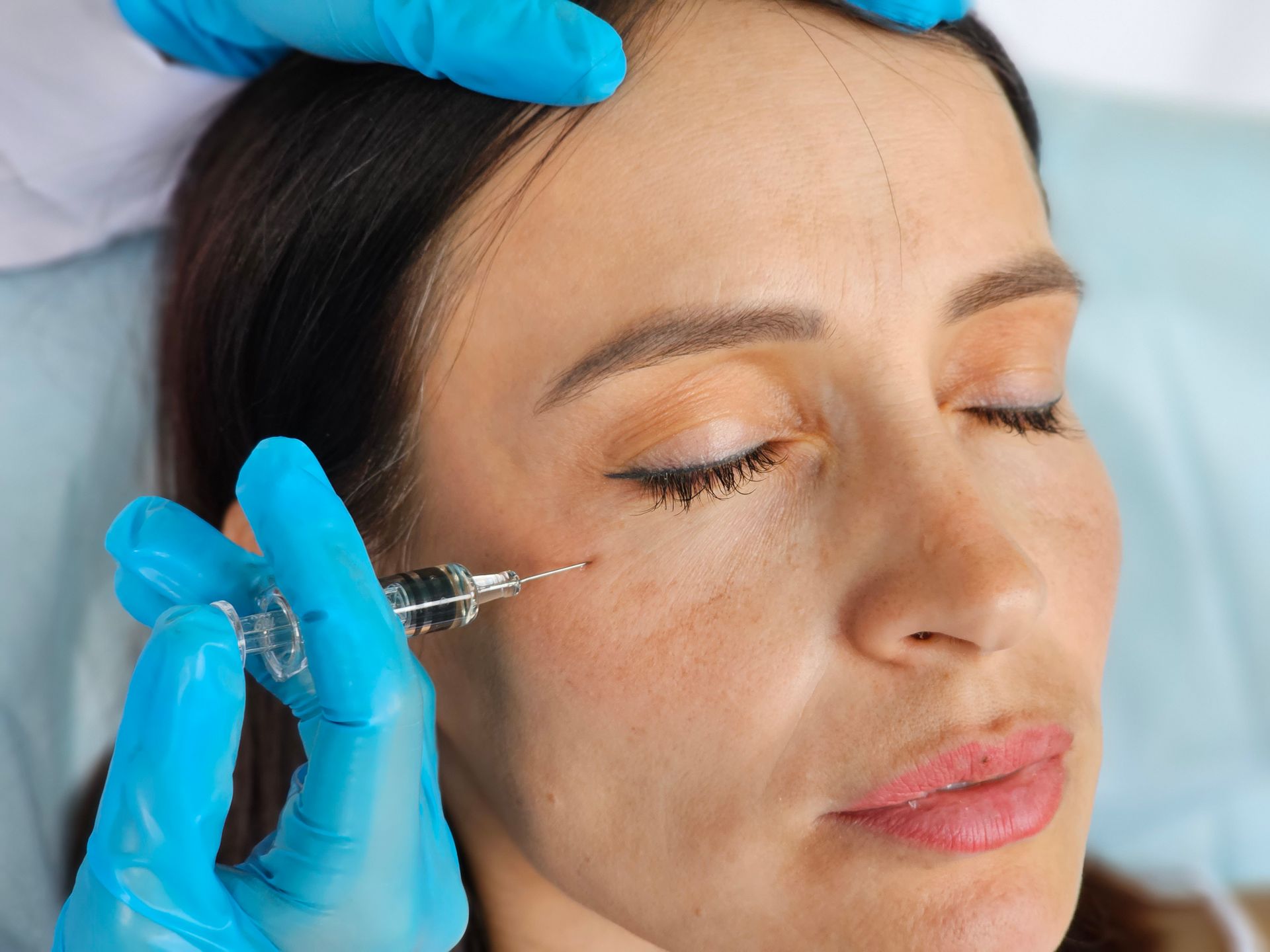 A woman is getting a botox injection in her eye.