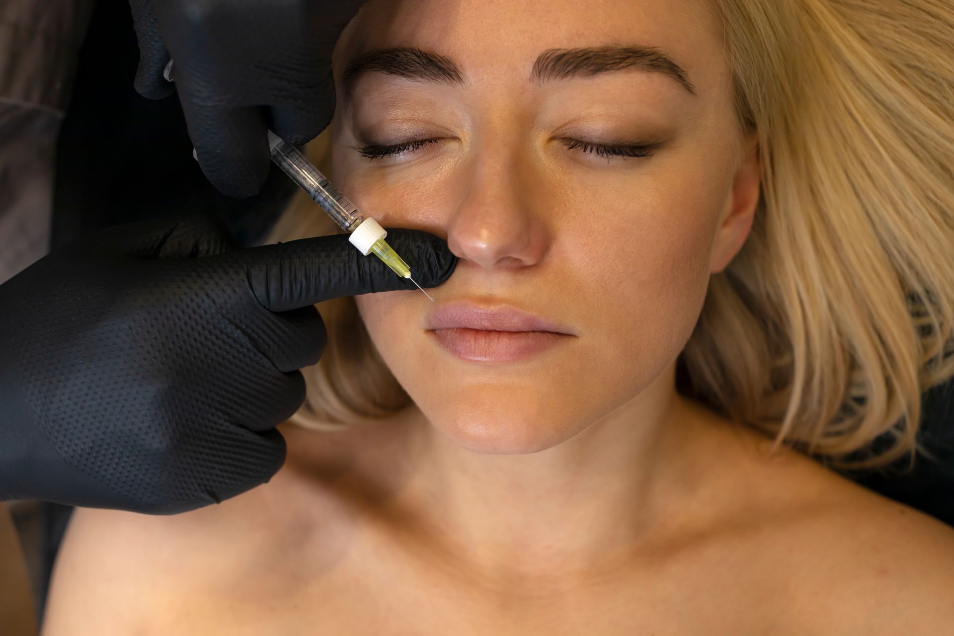 A woman is getting a botox injection in her nose.