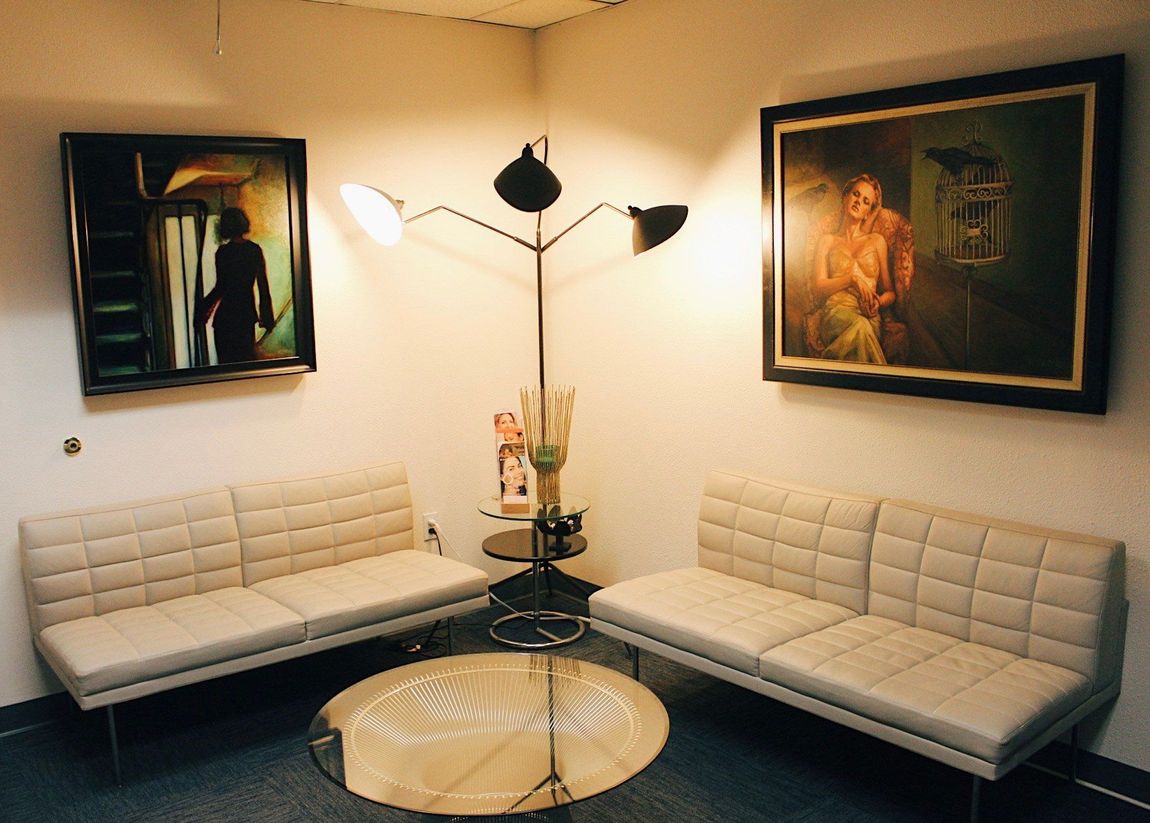 A waiting room with a couch and two paintings on the wall