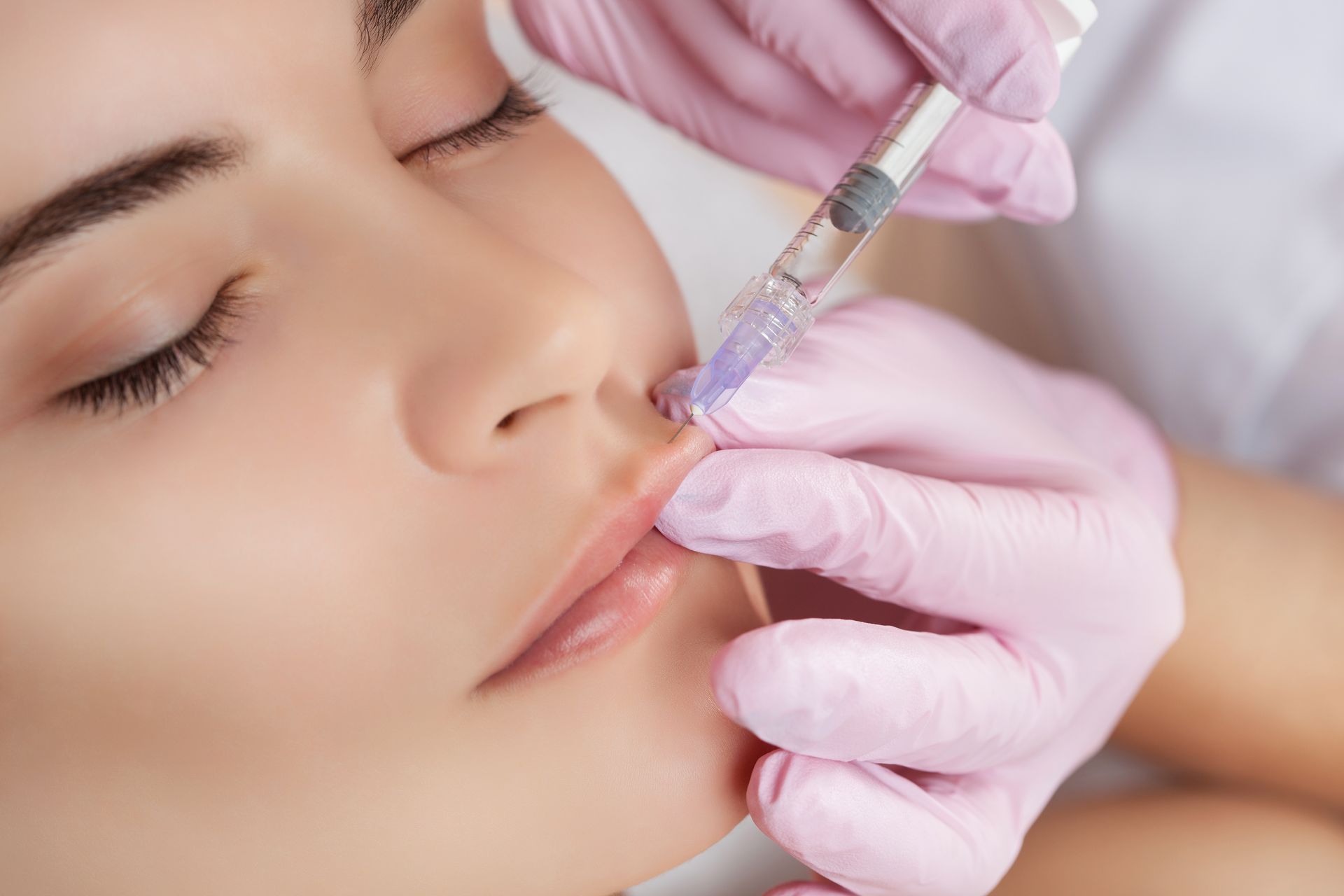 A woman is getting a botox injection in her lips.