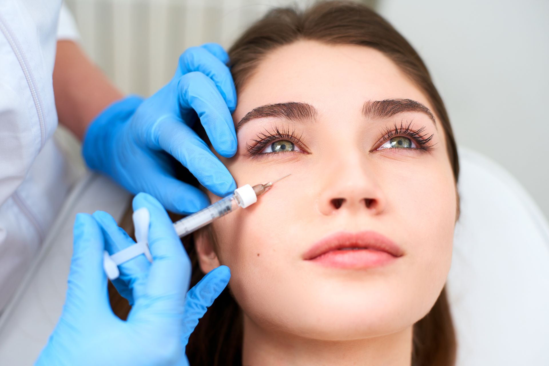 A woman is getting a botox injection in her face.