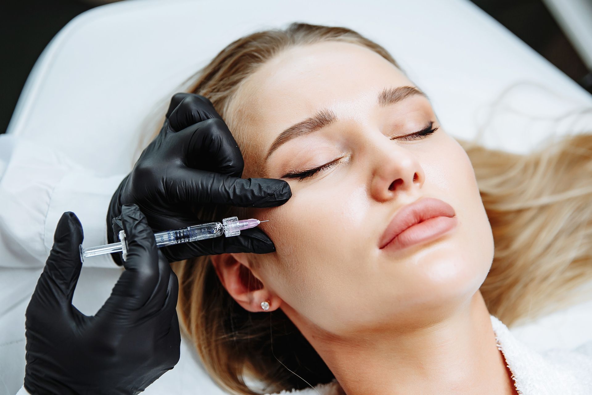 A woman is getting a botox injection in her face.