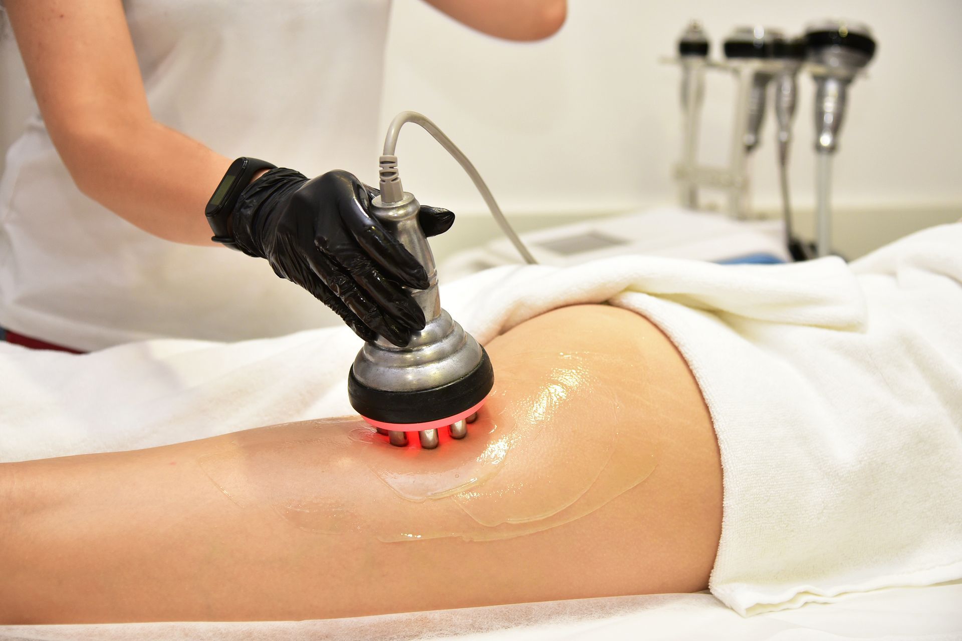 A woman is getting a cavitation treatment on her leg.