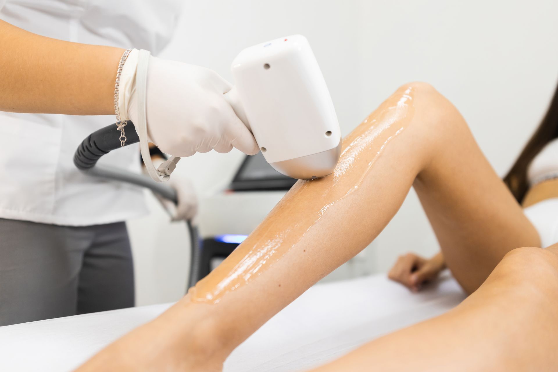 A woman is getting a laser hair removal treatment on her legs.