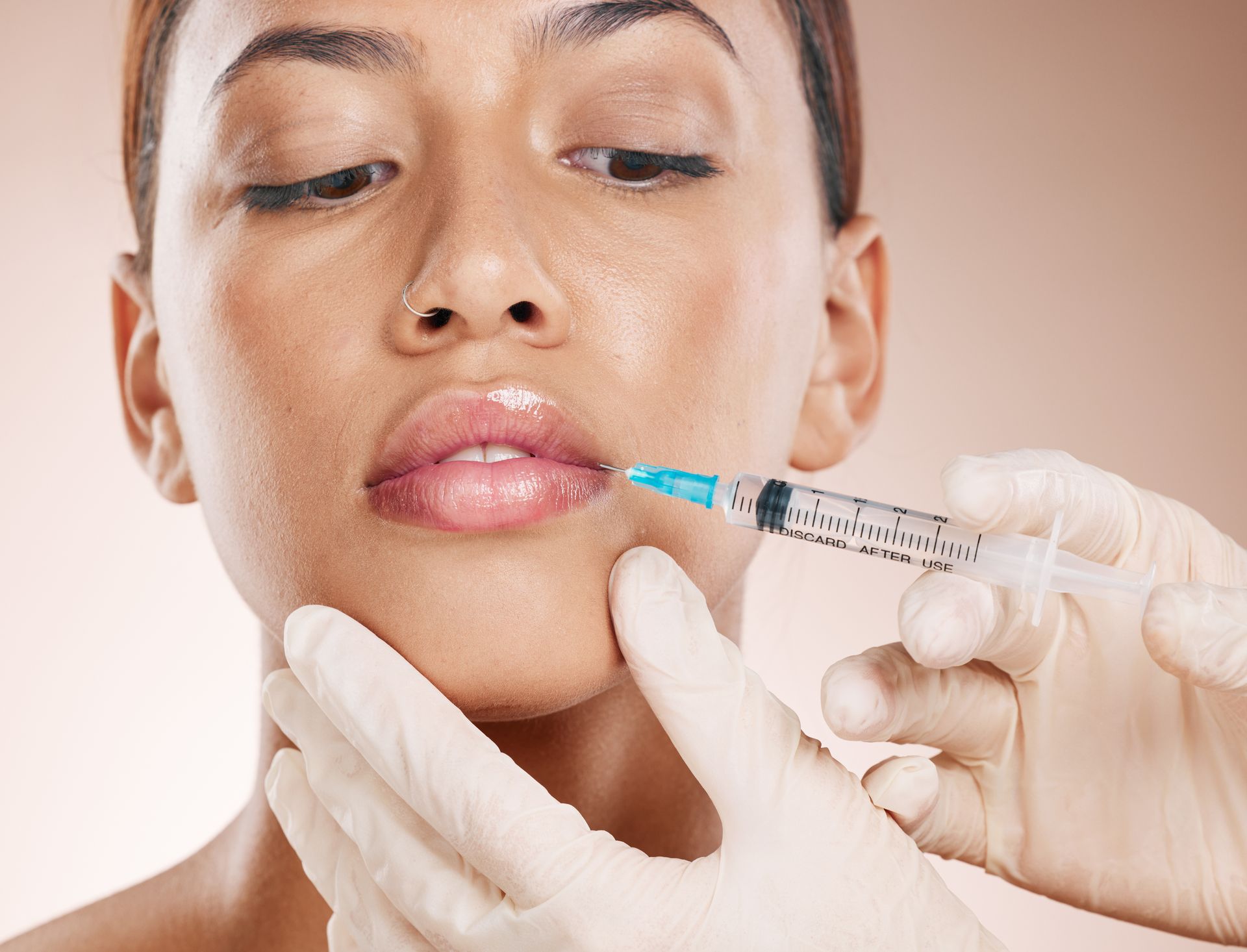 A woman is getting a botox injection in her lips.