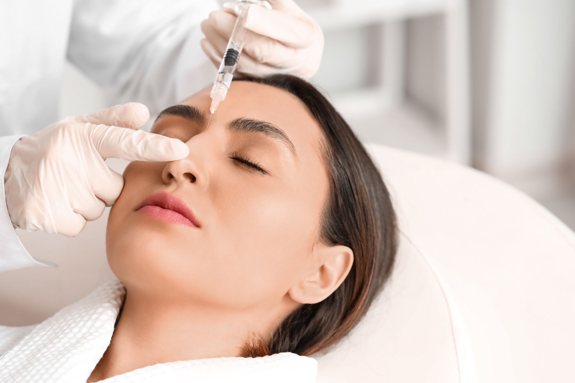 A woman is getting a botox injection in her forehead.