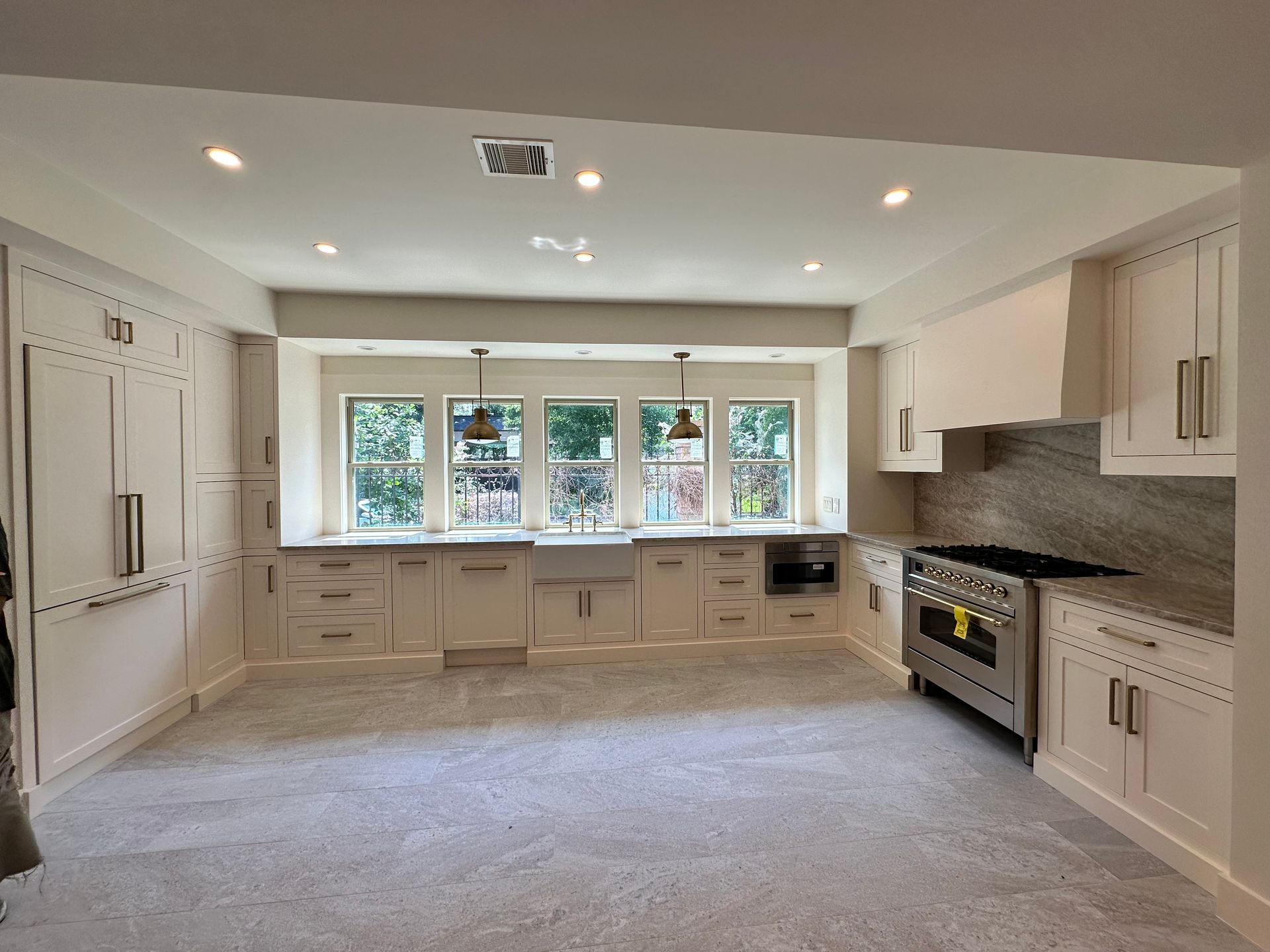 An empty kitchen with white cabinets and stainless steel appliances