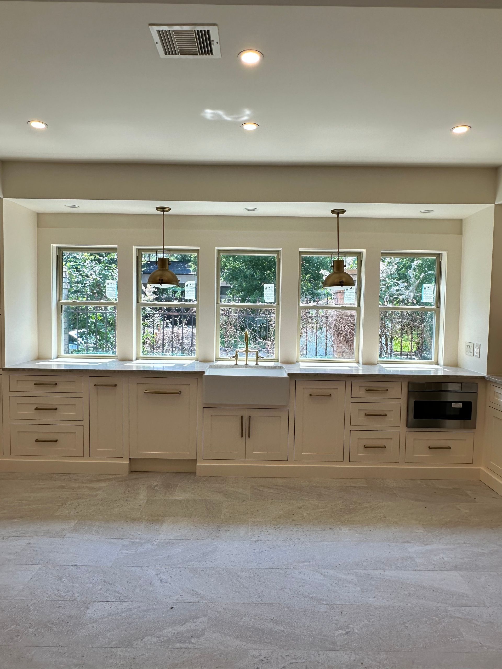 A kitchen with white cabinets and a large window