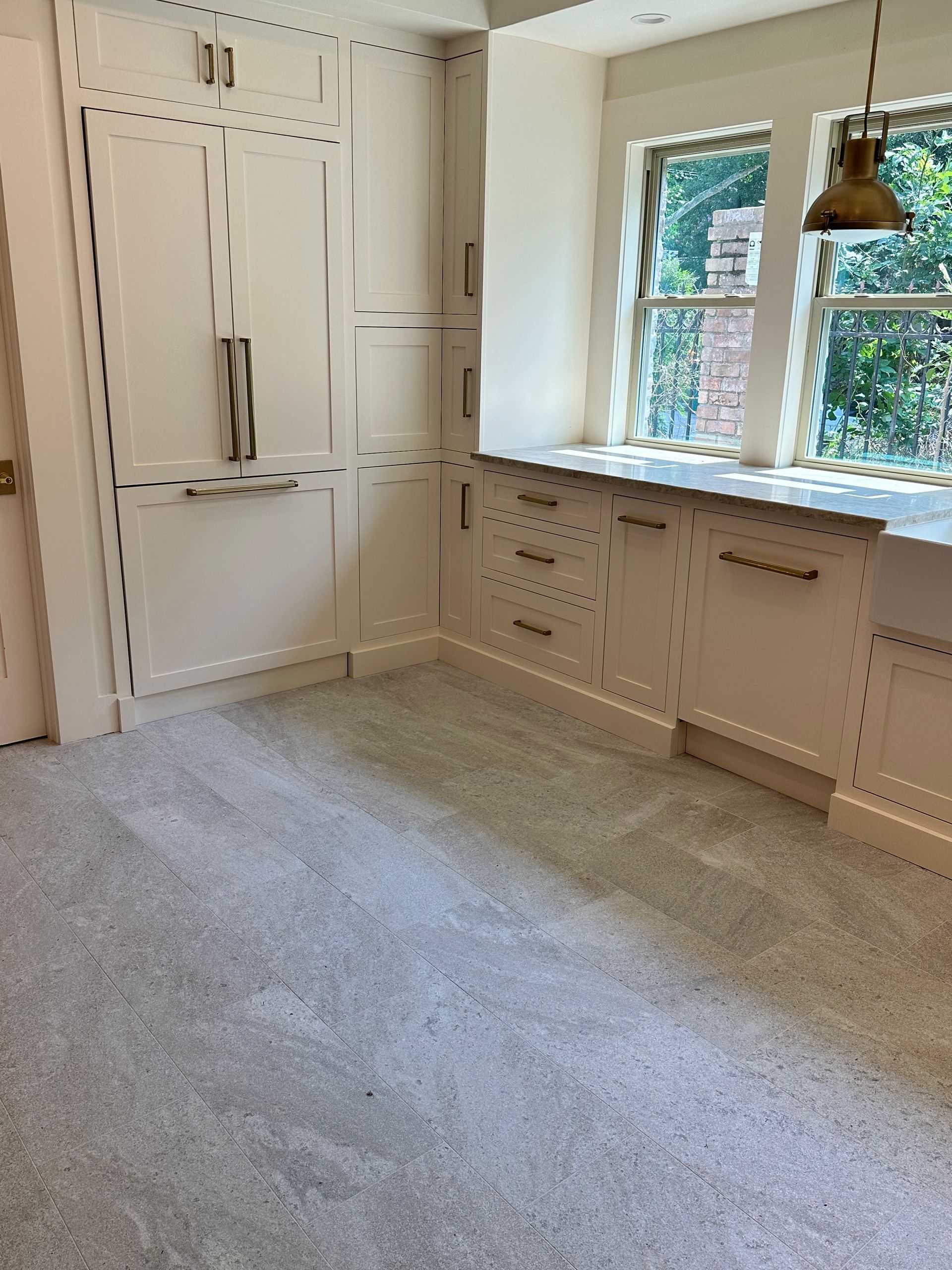 A kitchen with white cabinets and a gray carpet.