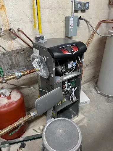 Portable machine in a utility room beside tanks, pipes, and a wall-mounted electrical box.
