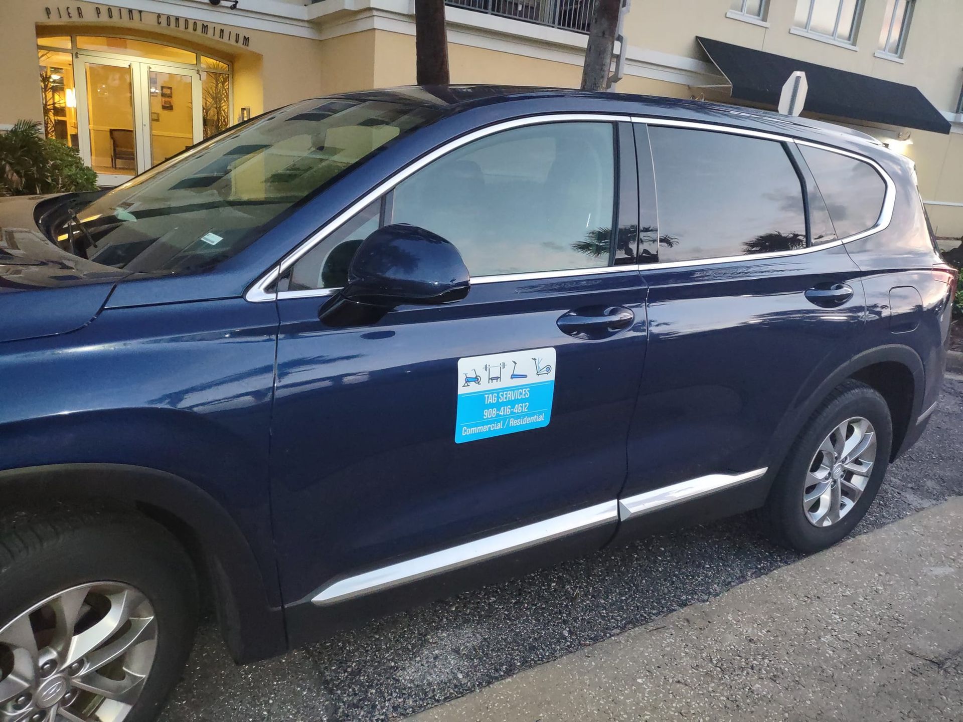 A blue suv is parked on the side of the road in front of a building.