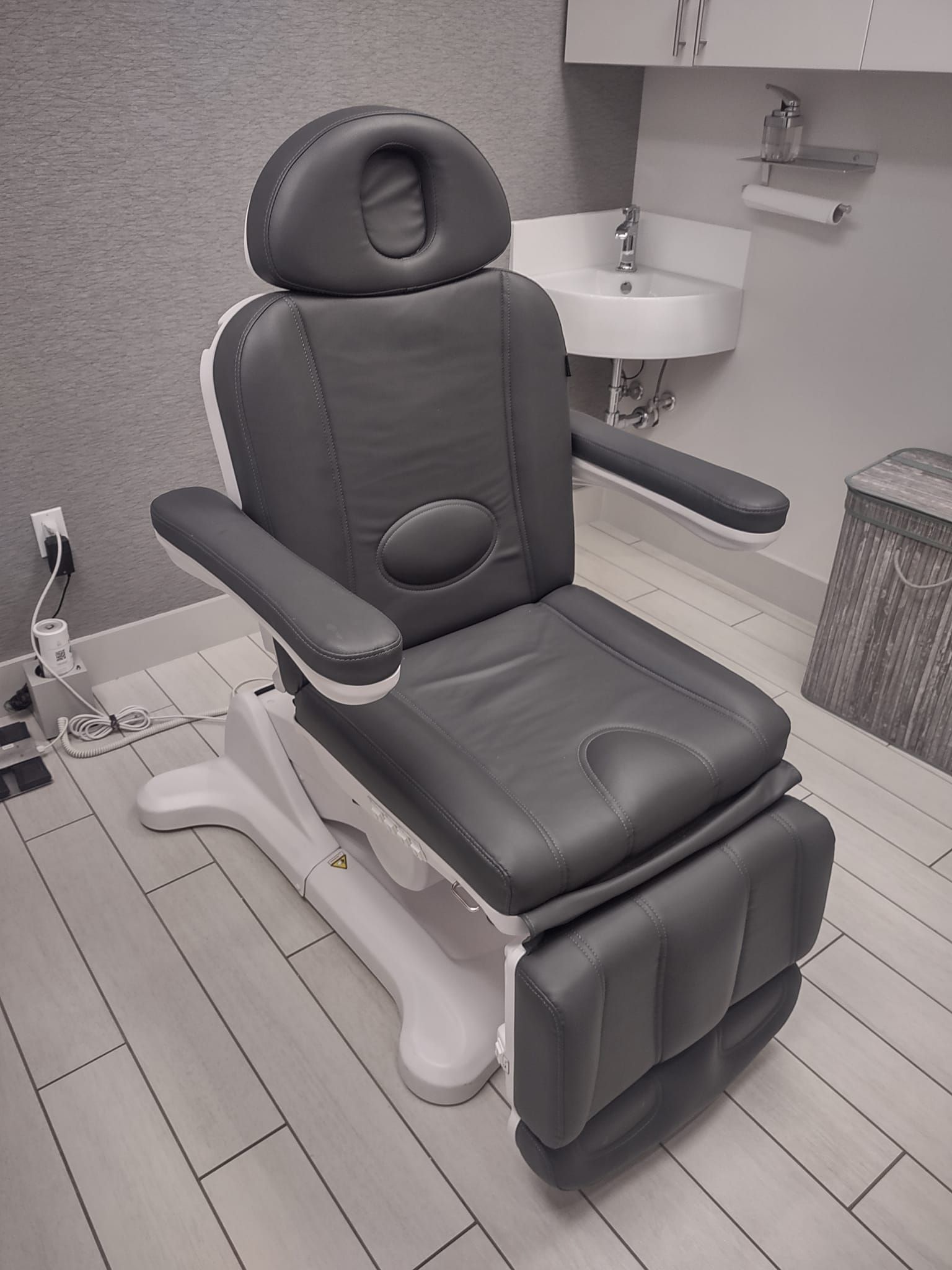 A gray chair is sitting in a room next to a sink.