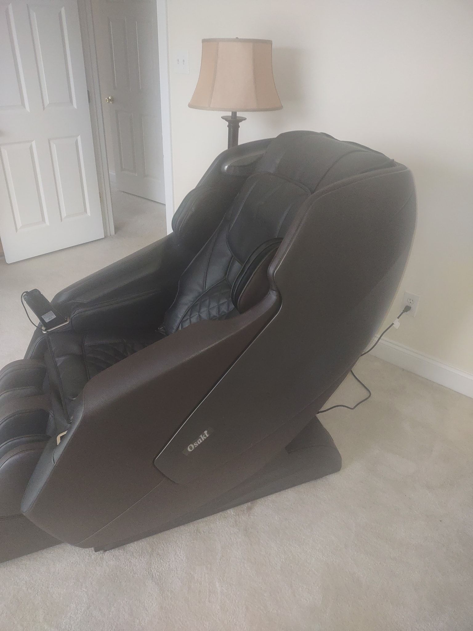 A massage chair is sitting in a living room next to a lamp.