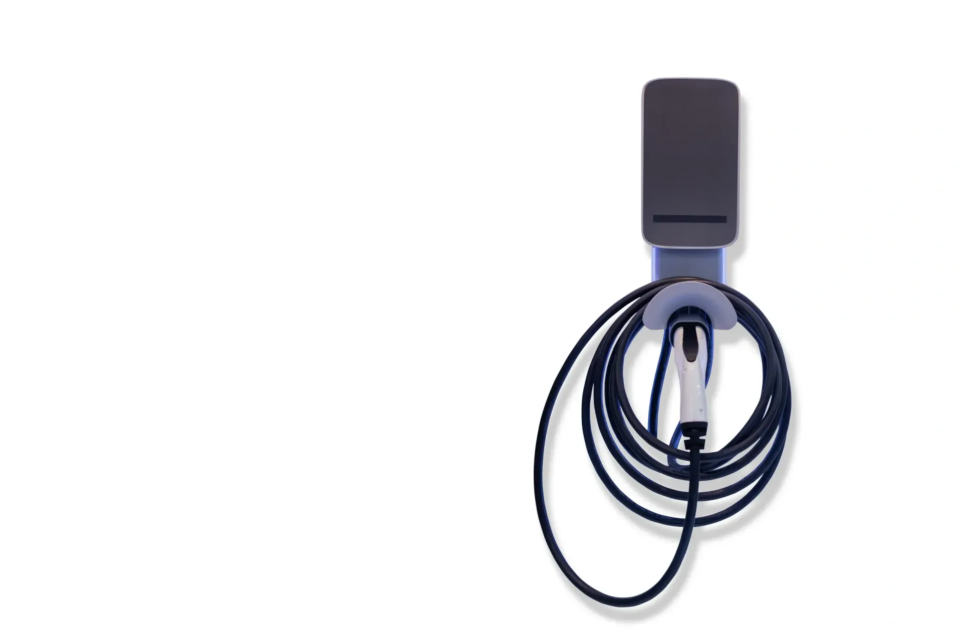 An electric vehicle charging station mounted on a white wall; black cable is coiled.