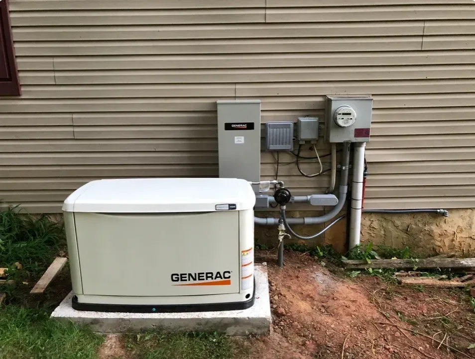 A Generac standby generator sits on a concrete pad beside a house, connected to electrical components.