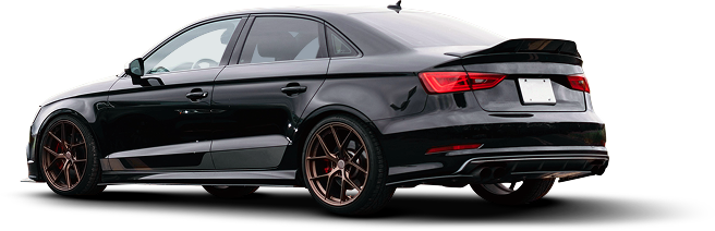 Black sedan with bronze wheels, spoiler, and a white background | Ken's Import Service