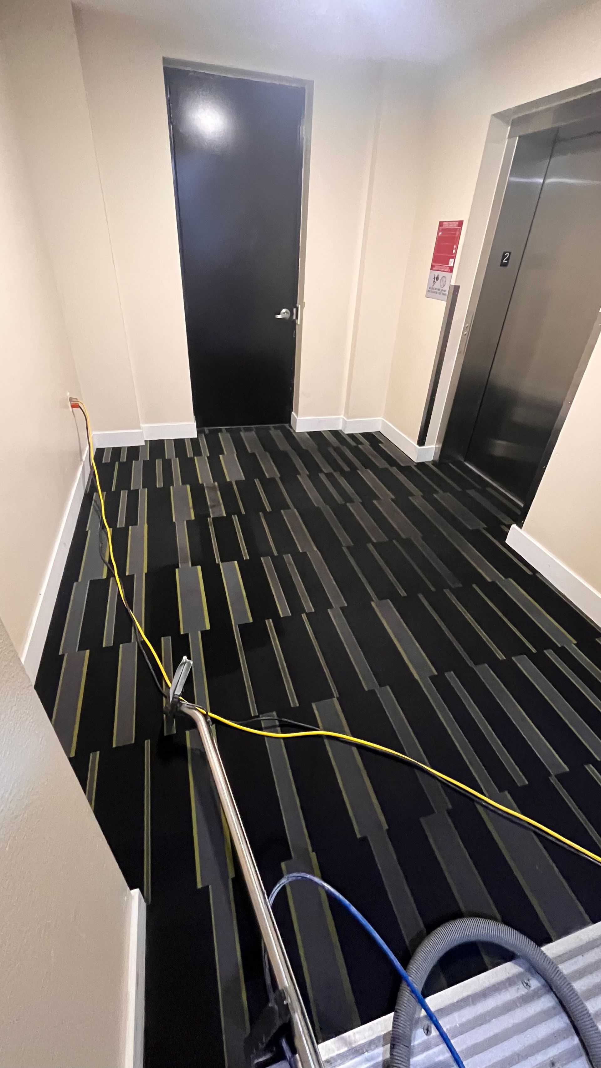 A vacuum cleaner is being used to clean a carpet in a hallway.