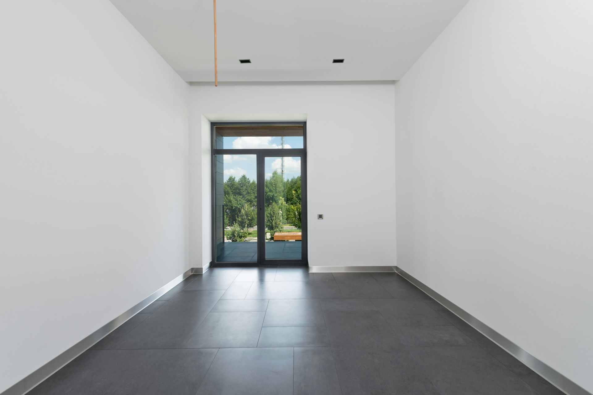 An empty room with white walls and a black tile floor.
