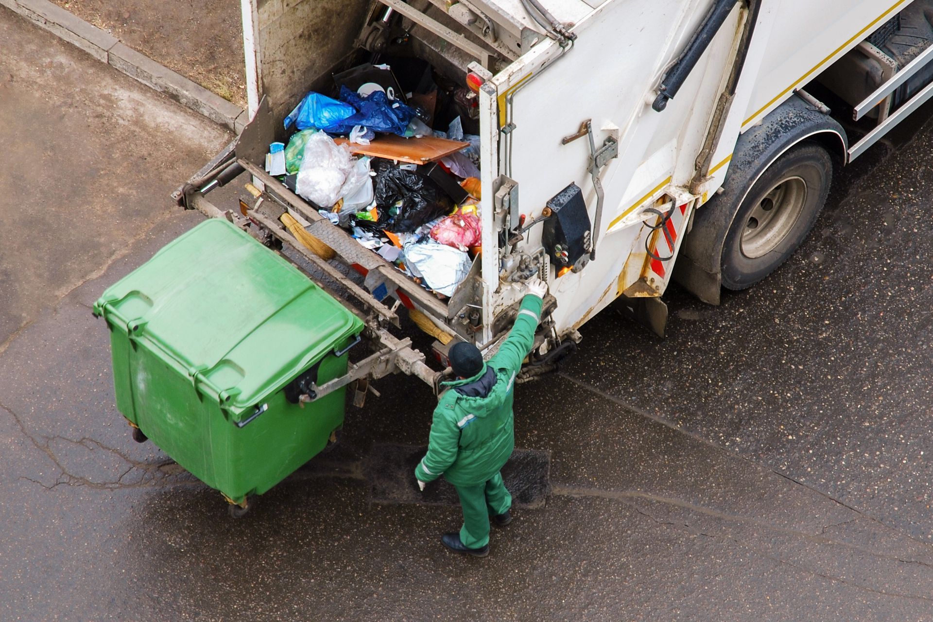 a man is loading garbage into a garbage truck .