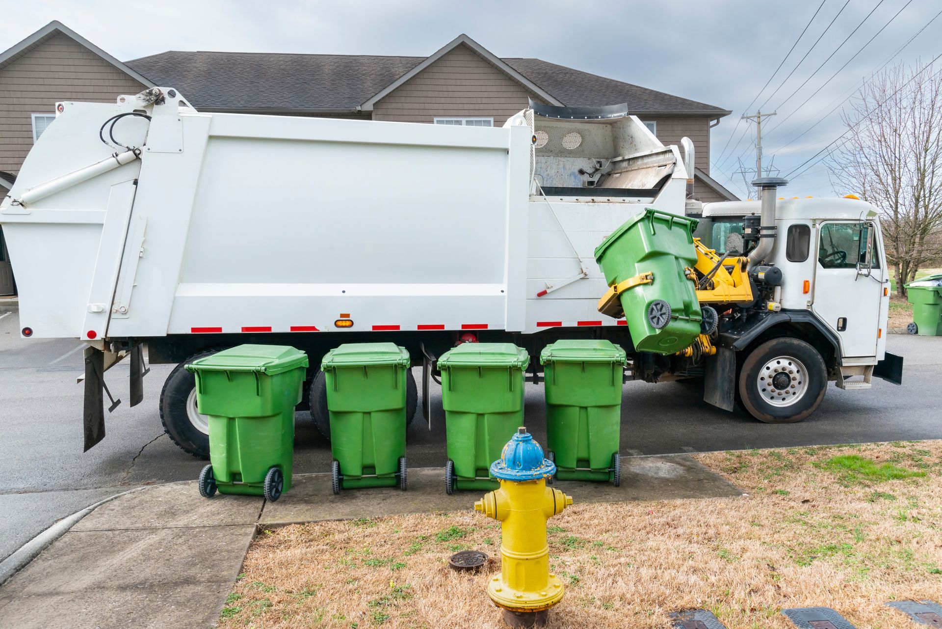 a garbage truck parked on the side of the road next to a fire hydrant
