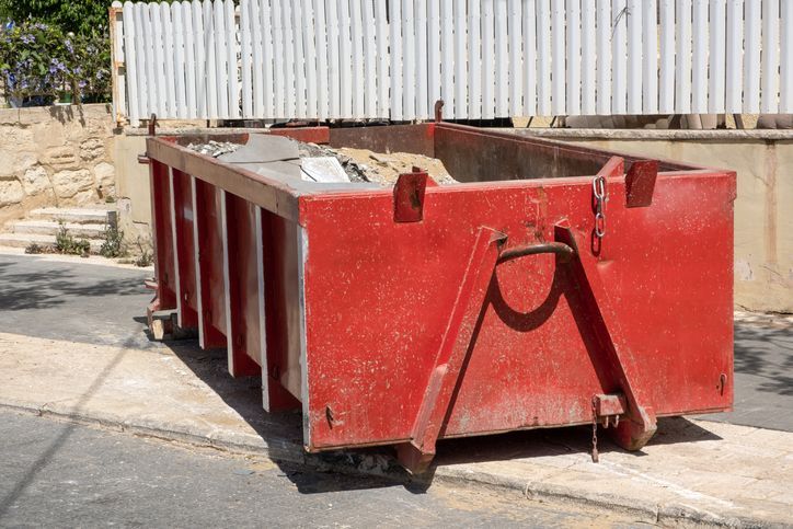 Construction waste in a half empty Red dumpster. Waste metal tank container filled with construction waste, rubble near a construction site